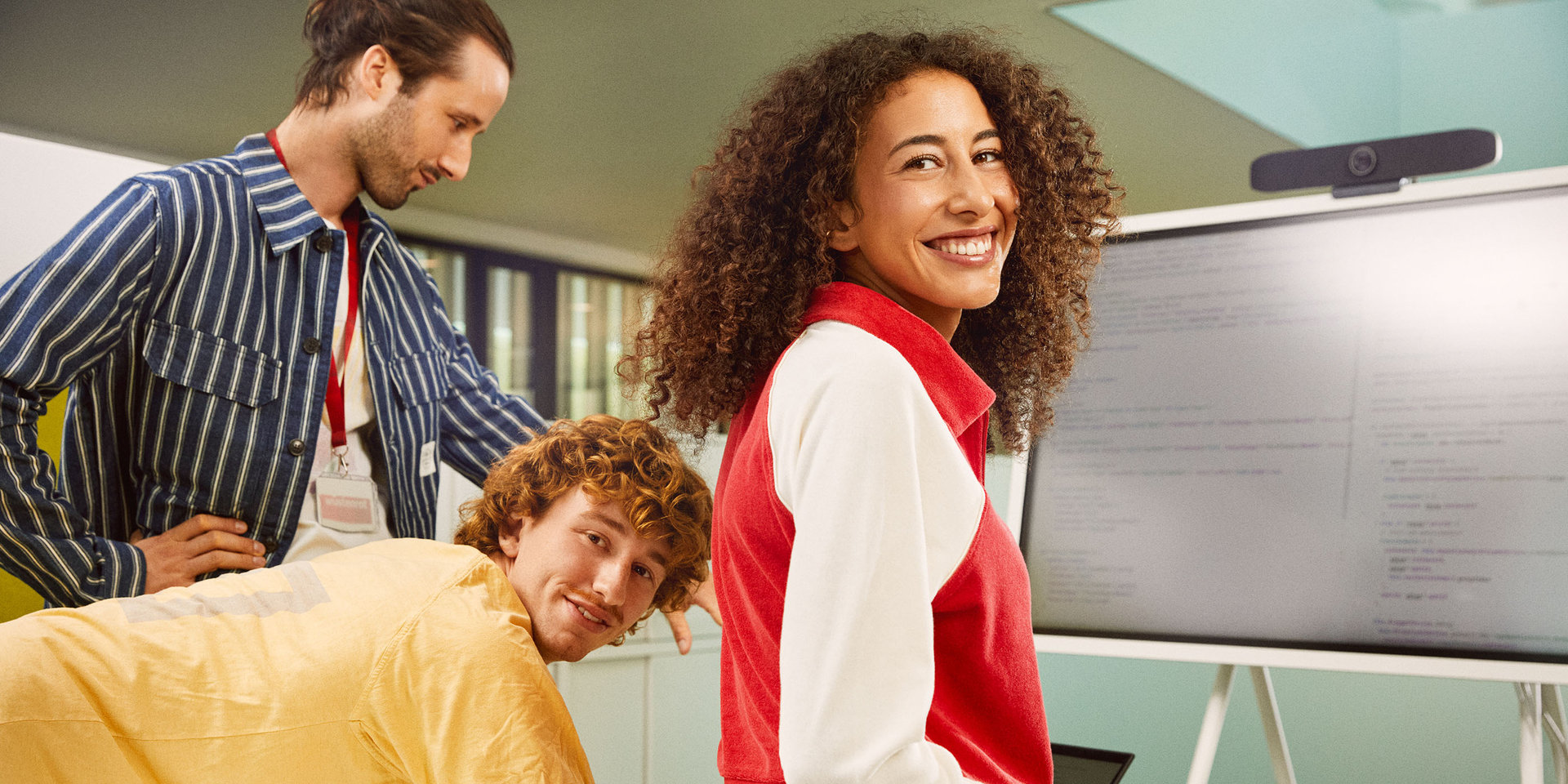 eine Kollegin und zwei Kollegen betrachten gemeinsam Programmiercode auf einem Bildschirm